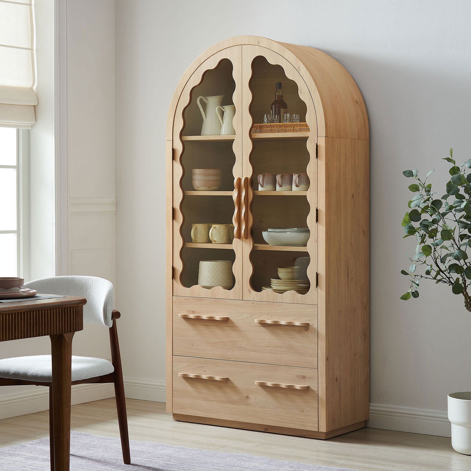 Light oak arch cabinet styled in a dining room with dishes and decor on display || EEI-7589-LOA || front_angle_room