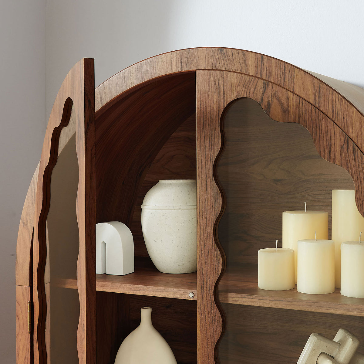 Arched upper shelves of the walnut cabinet styled with candles and sculptural decor || EEI-7589-WAL || detail_room