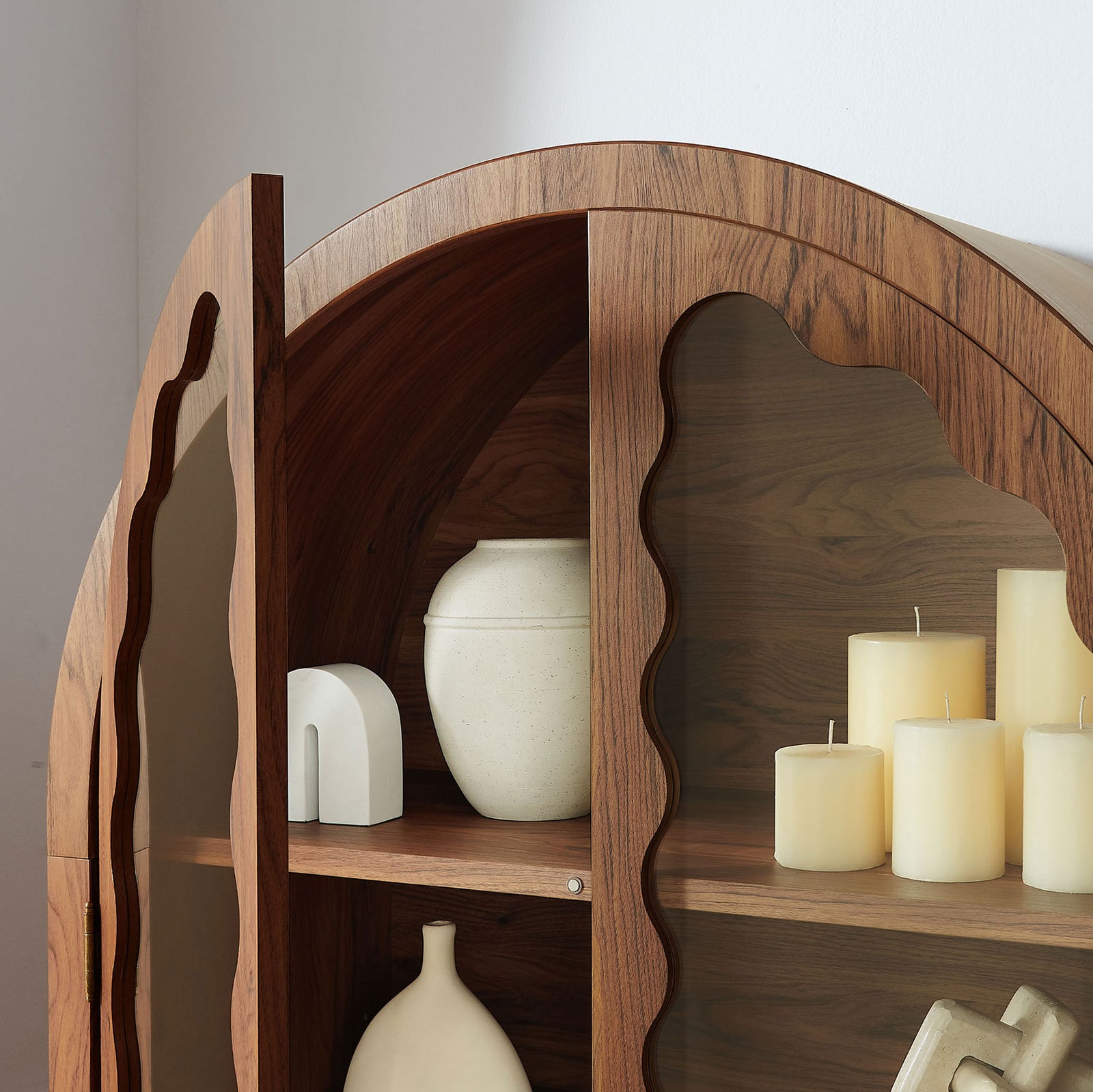 Arched upper shelves of the walnut cabinet styled with candles and sculptural decor || EEI-7589-WAL || detail_room