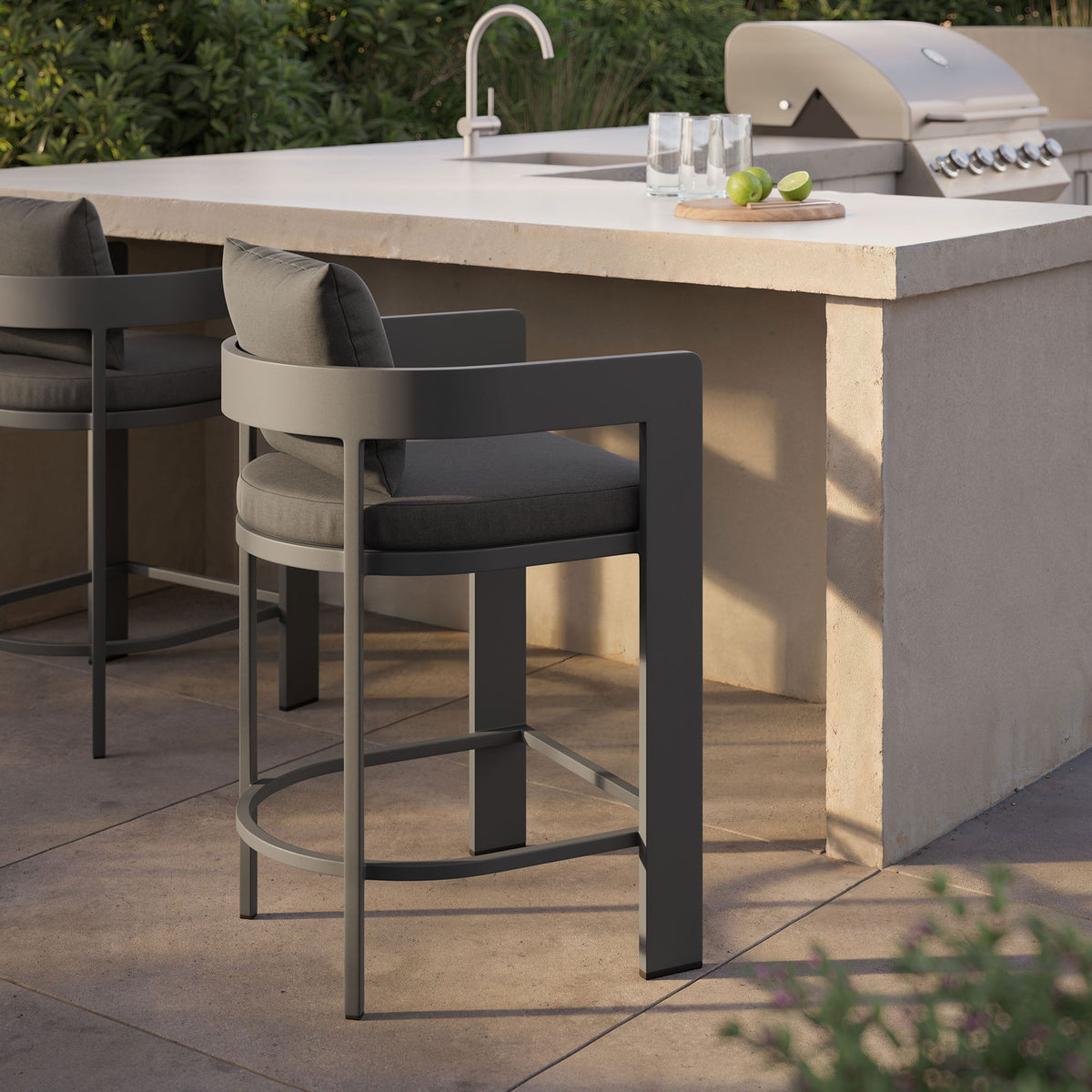 Charcoal Tahoe counter stool placed by an outdoor bar, creating a stylish spot for poolside entertaining. || EEI-7596-CHA || front_angle_room
