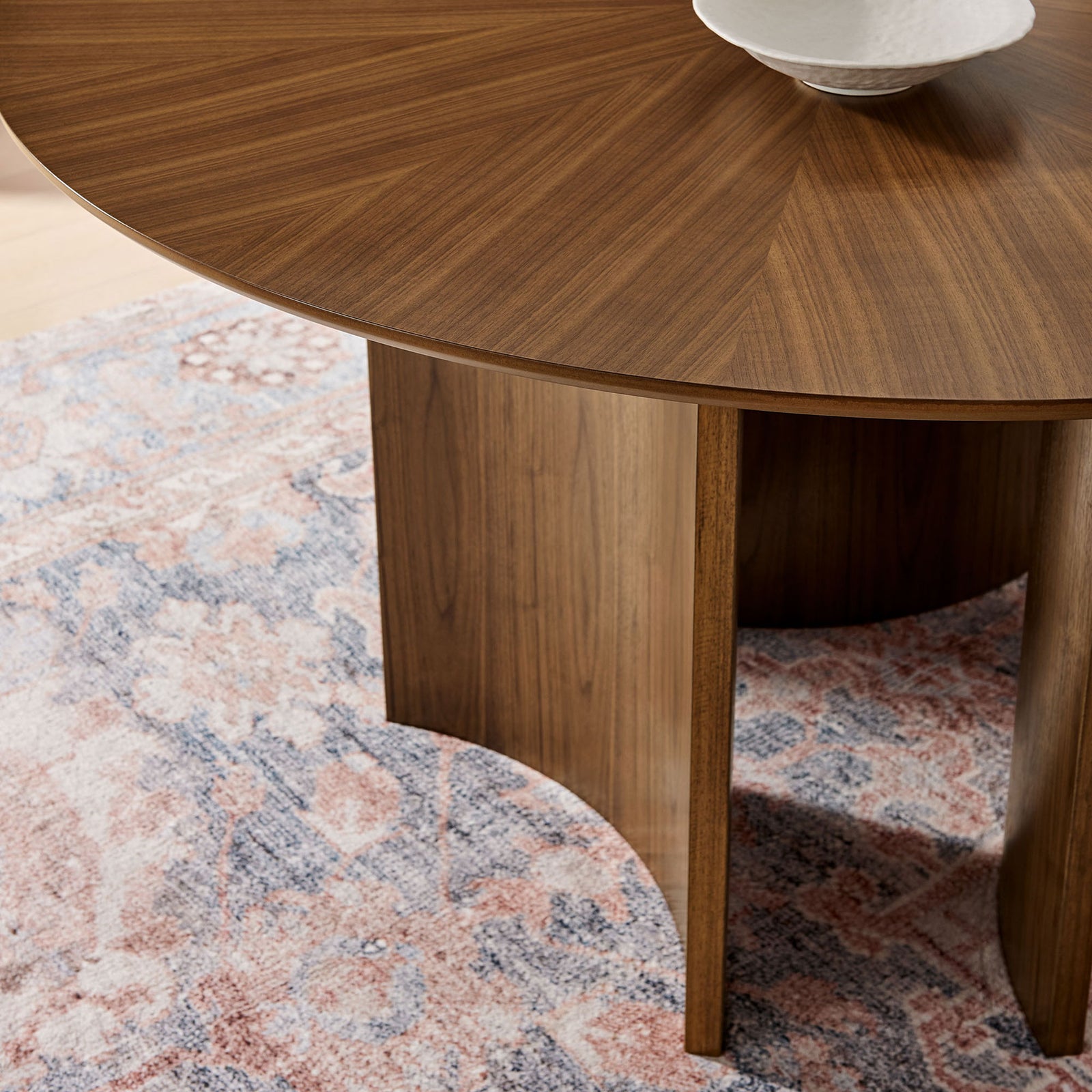 Walnut round dining table corner styled on a patterned rug with smooth edge and rich veneer grain || EEI-7603-WAL || detail_room