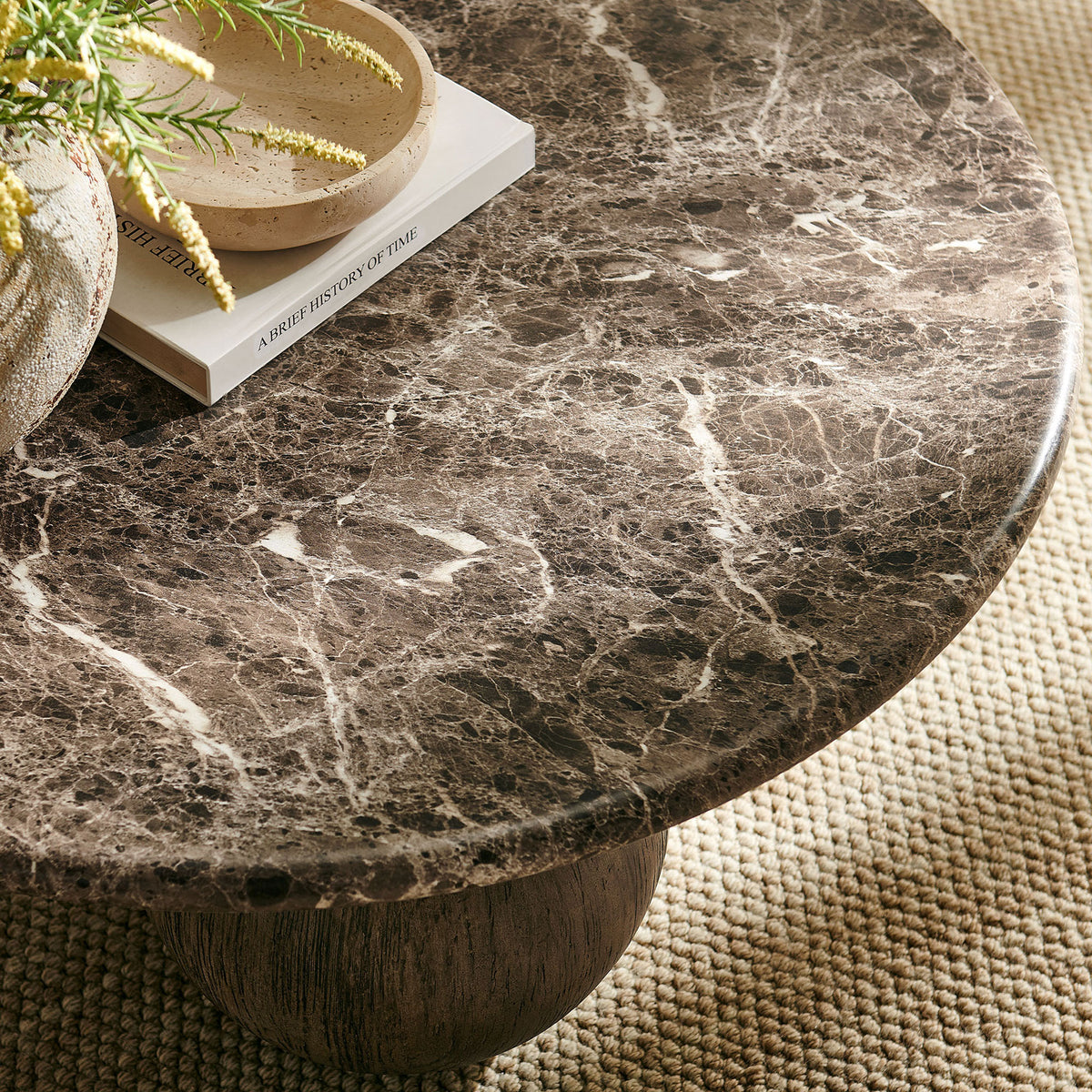 Marble-look round coffee table styled with books and decor on a textured neutral rug || EEI-7622-EMP || detail_room