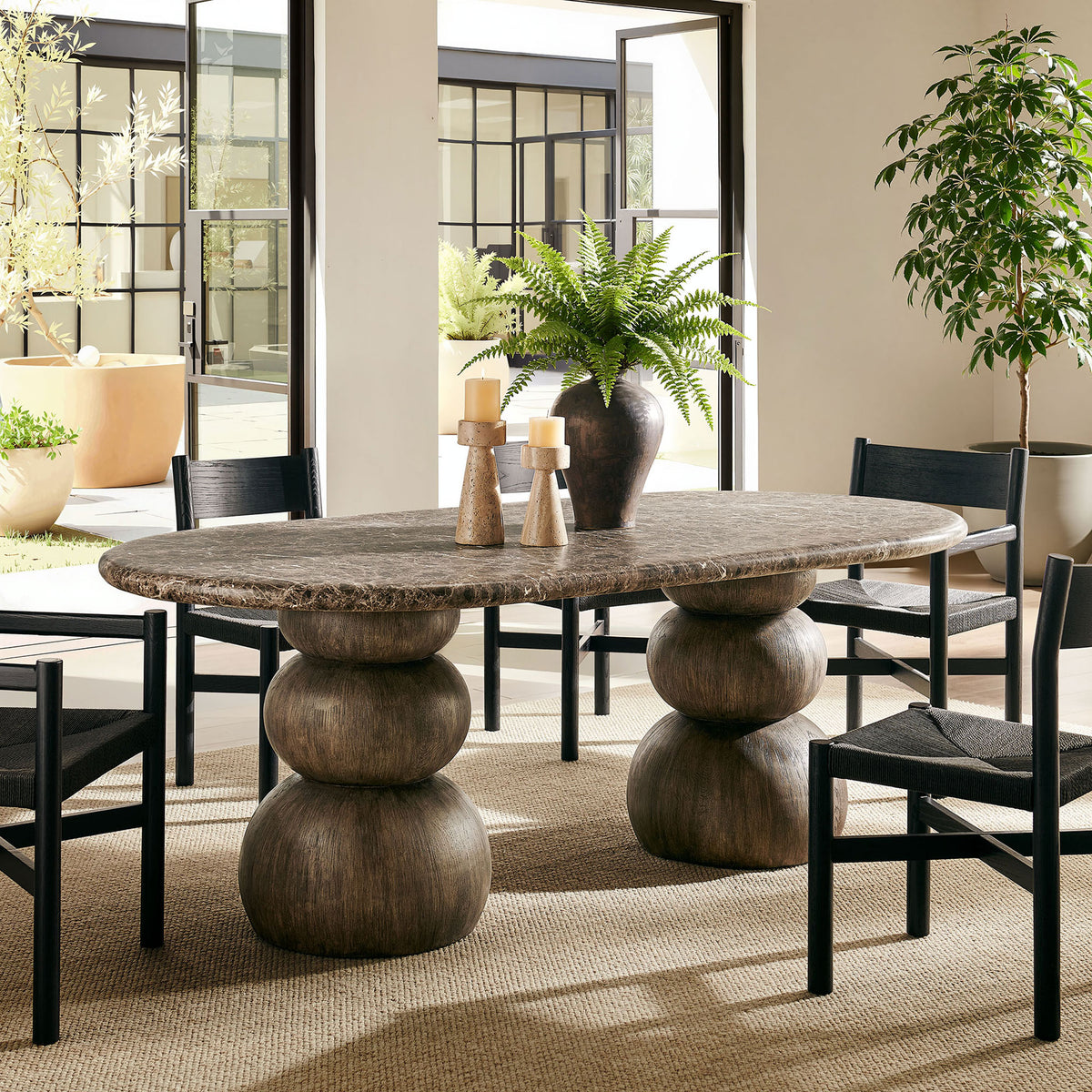 Oval dining table anchors a modern indoor seating area with its sculptural double pedestal base || EEI-7623-EMP || front_angle_room