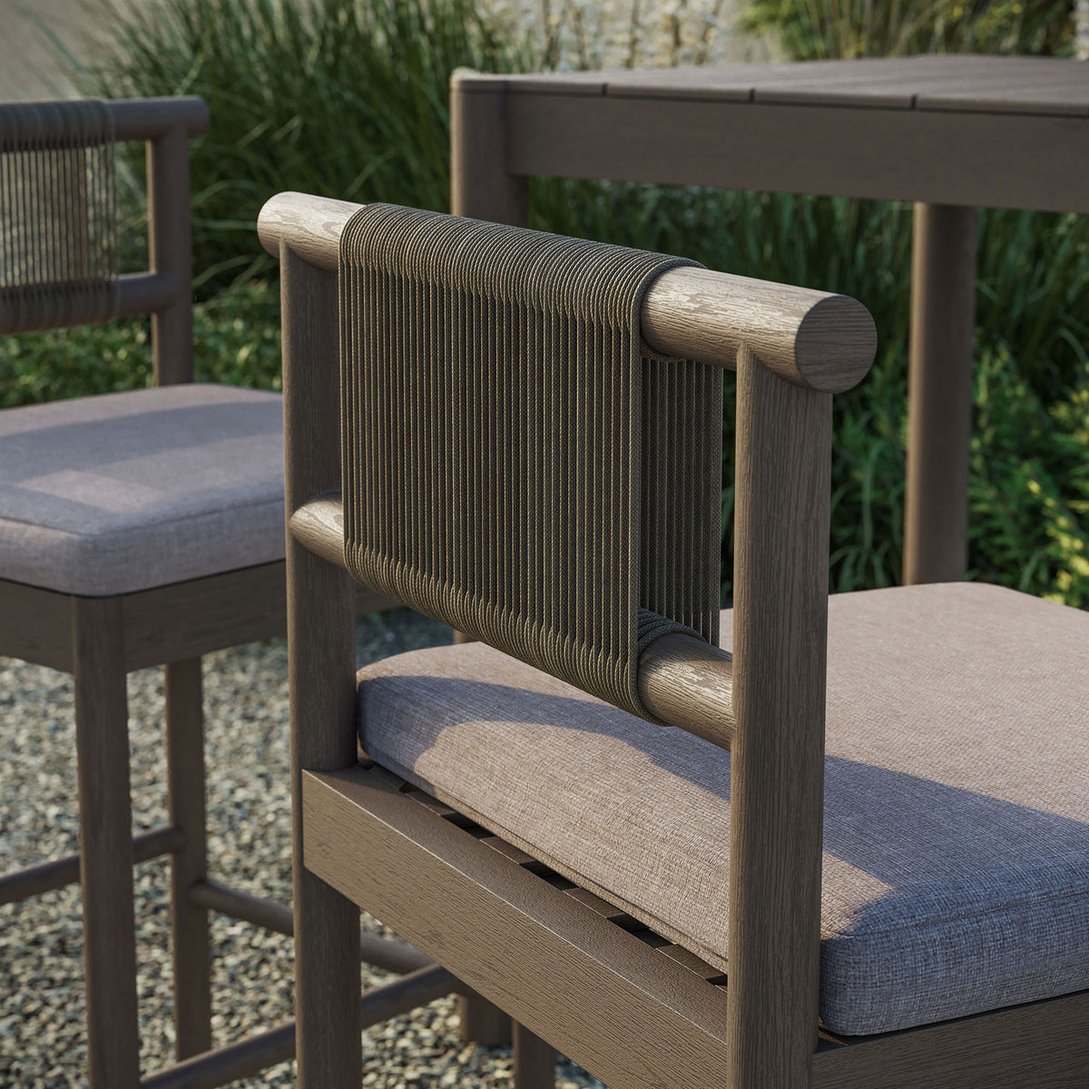 Outdoor close-up of weathered gray bar stool rope back and pebble cushion beside bar table || EEI-7626-WGR-PEB || detail_room