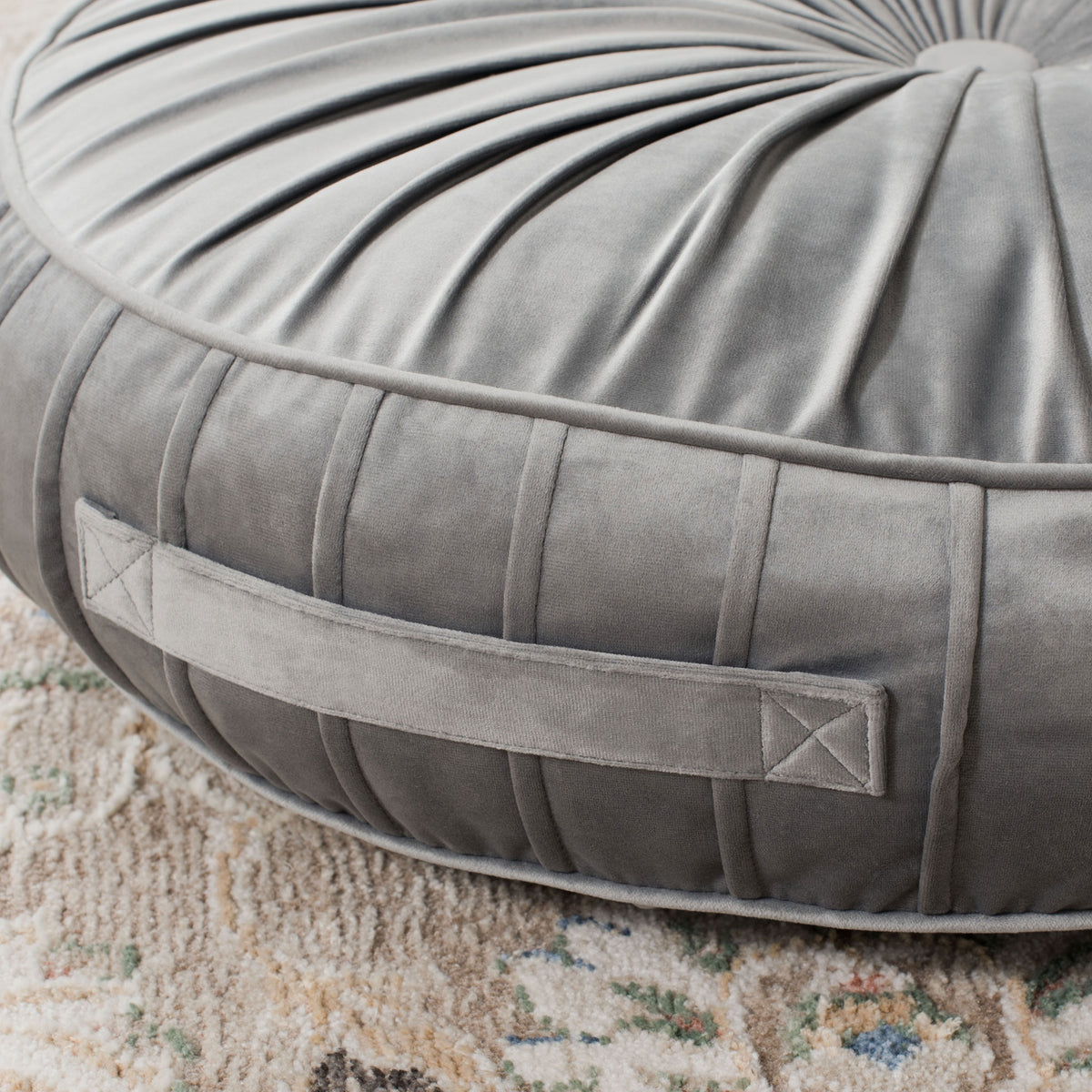 Gray floor pillow features a reinforced fabric carry handle, pleated sides, and neat edge piping