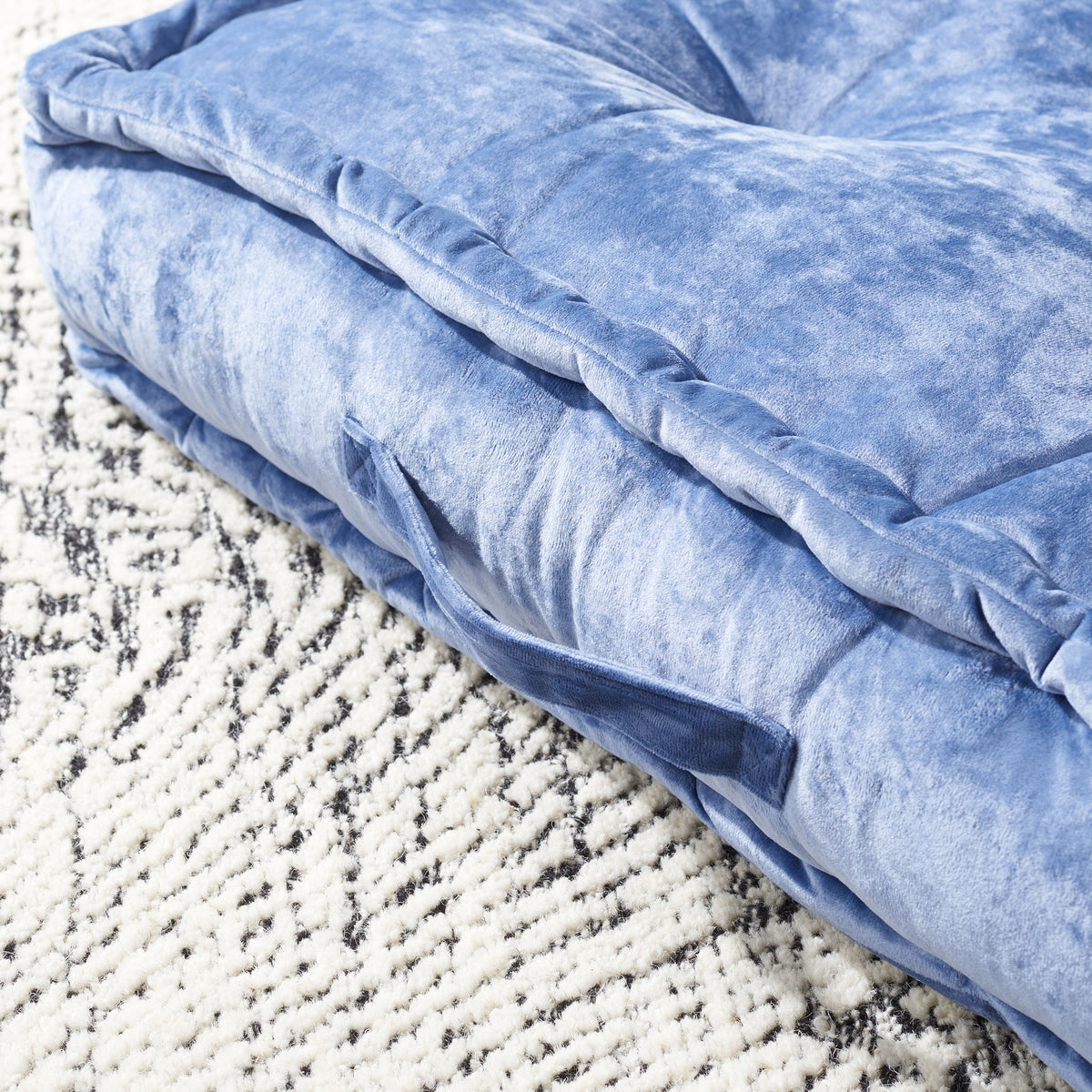 A blue fabric carry handle nestles beneath softly piped edges and velvety cushioning. || FLP1001A-2424 || handle_room
