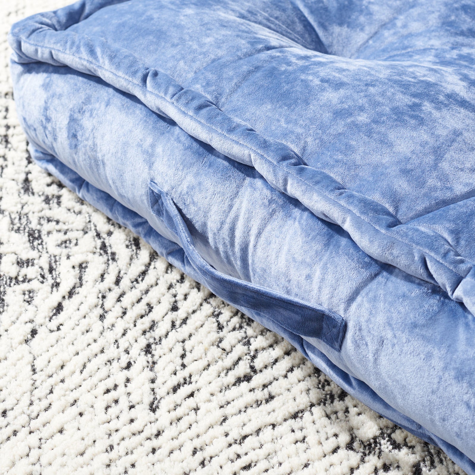 A blue fabric carry handle nestles beneath softly piped edges and velvety cushioning. || FLP1001A-2424 || handle_room