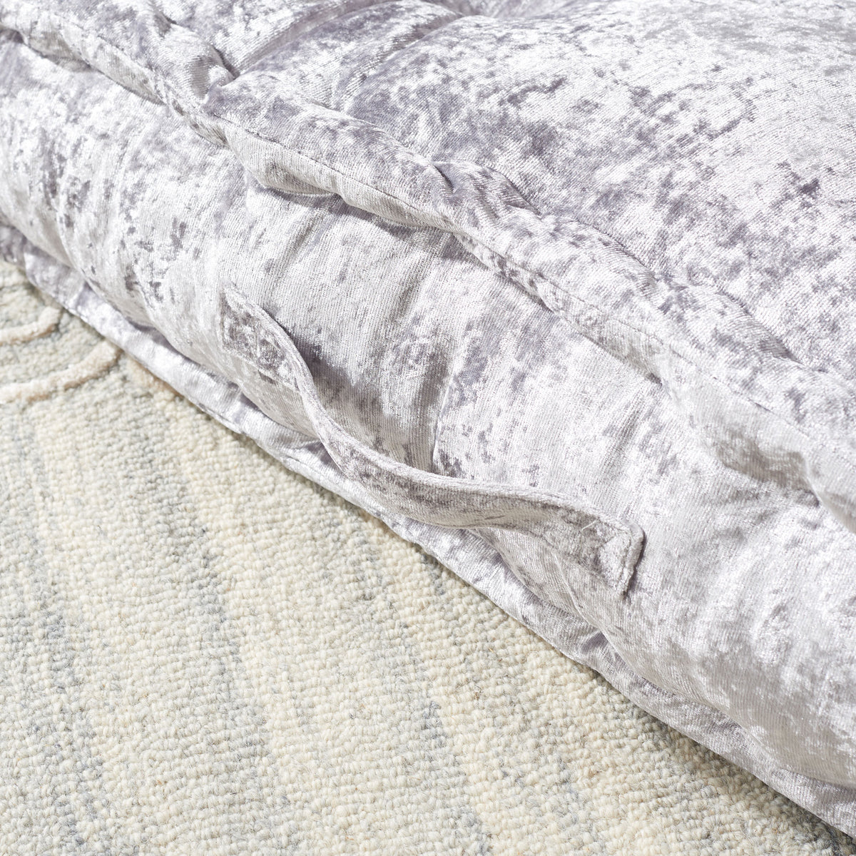 A silver fabric handle accents the pillow's lustrous, softly padded side.