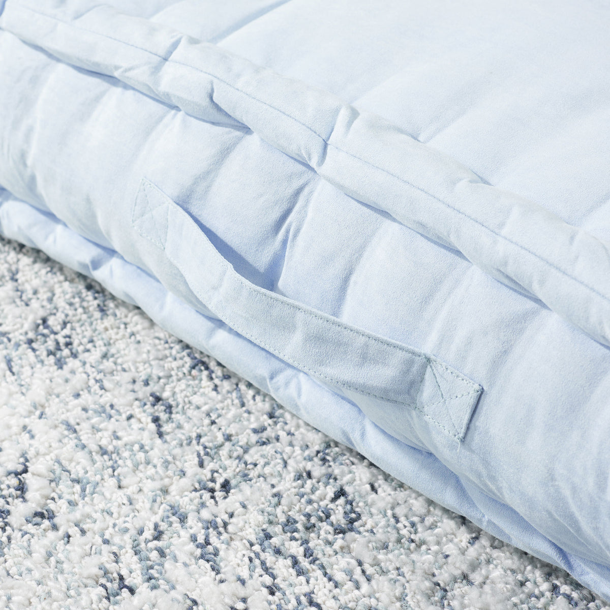 Pale blue floor pillow with a sewn fabric carry handle and generously cushioned edges || FLP1002A || handle_room