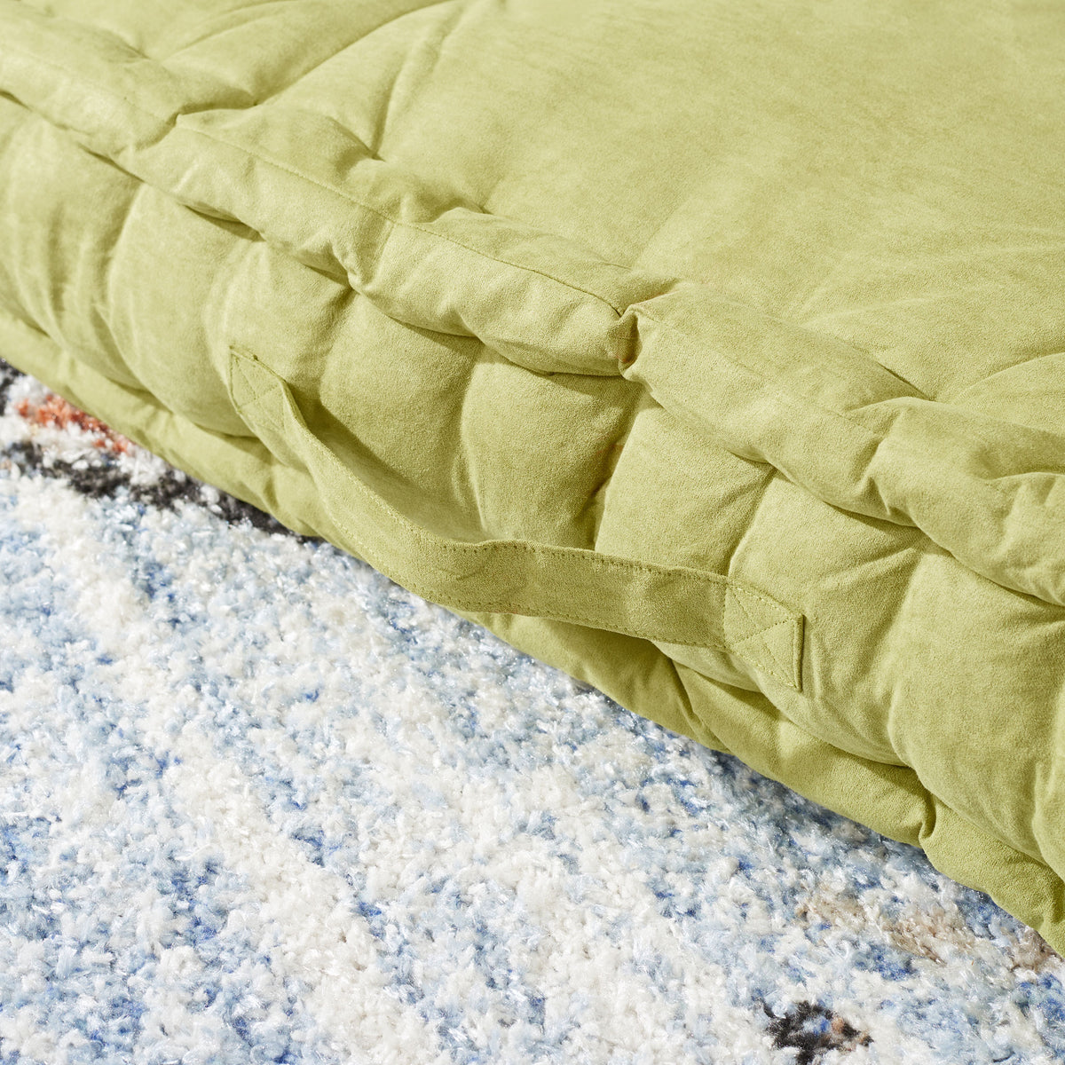 Light green floor pillow with a sewn carry handle and plush, gathered side panels