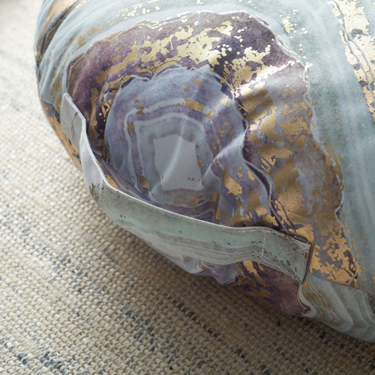 A sewn fabric handle complements violet and aqua swirls with gold accents