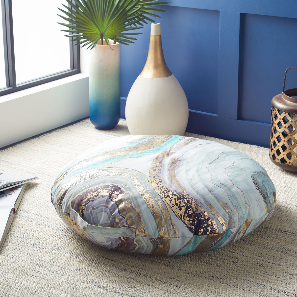 Thick round floor pillow with aqua, violet, and gold marbling and an easy-carry fabric loop