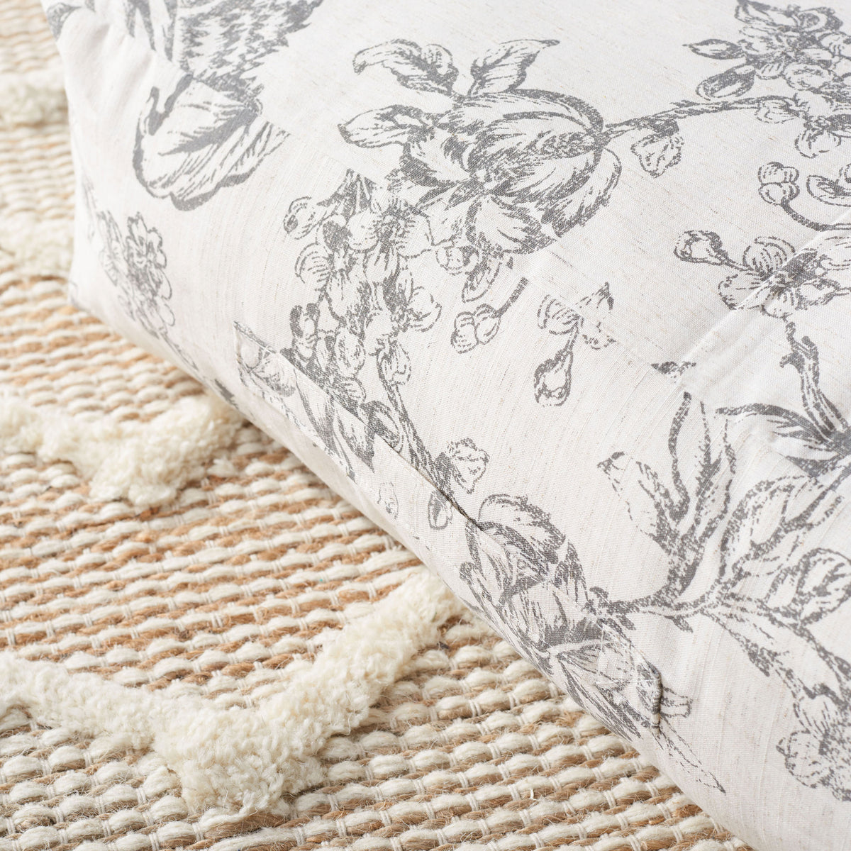 Gray floral branches spread across the floor pillow's textured beige fabric. || FLP1011A || detail_room
