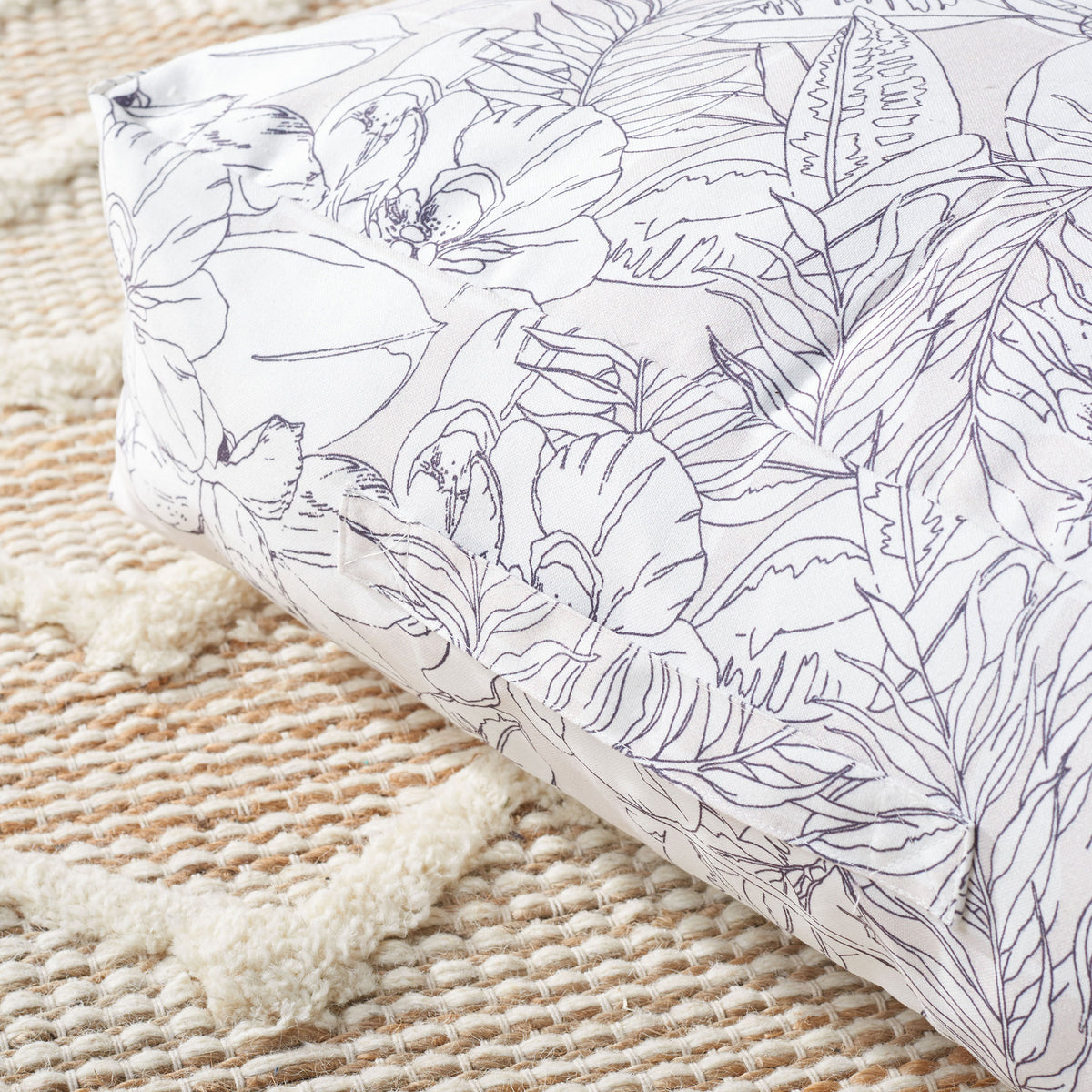 Soft beige fabric features intricate black floral outlines and neatly tailored corner seams.