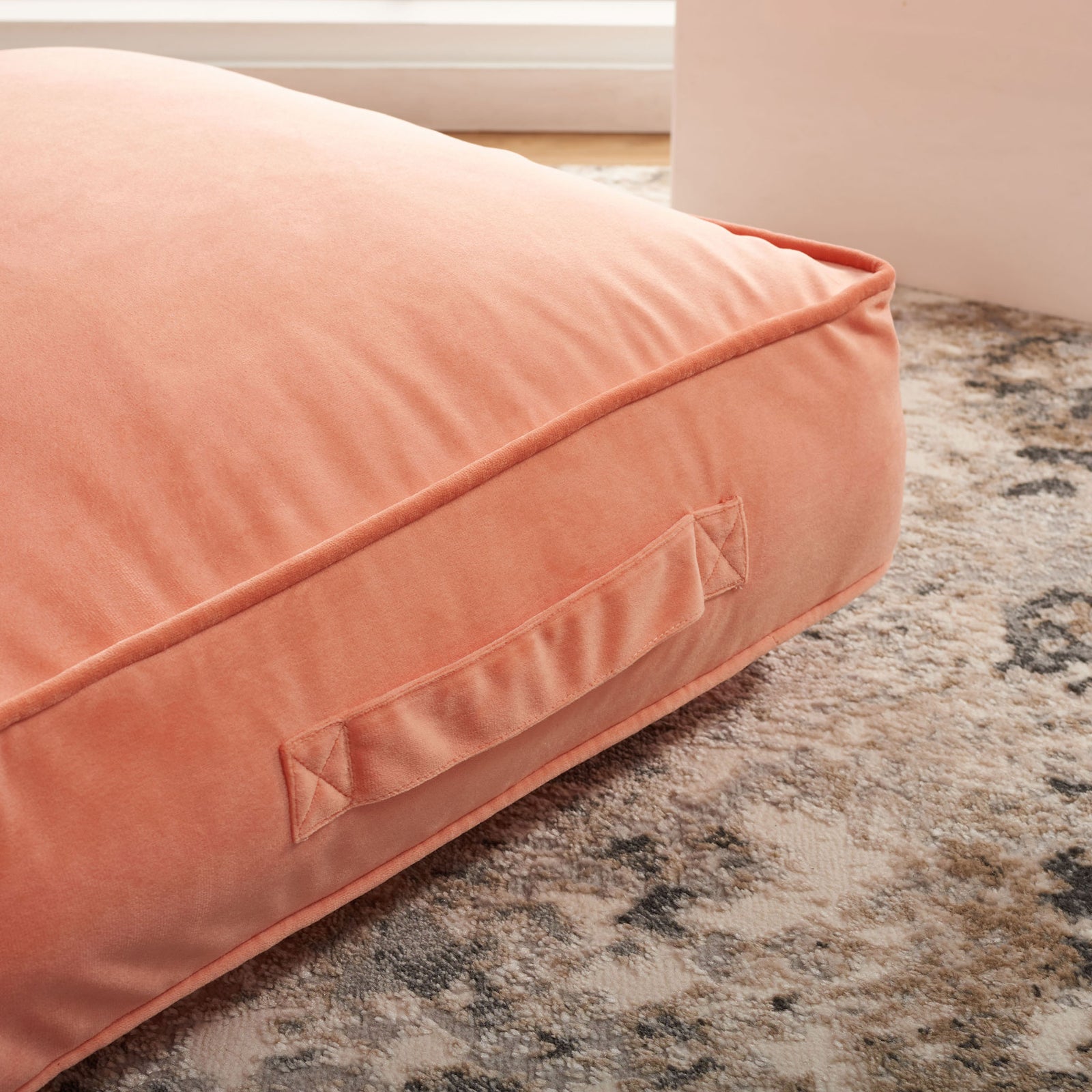 Peach floor pillow pairs a cushioned top with a stitched fabric handle along its piped side || FLP1015A || handle_room