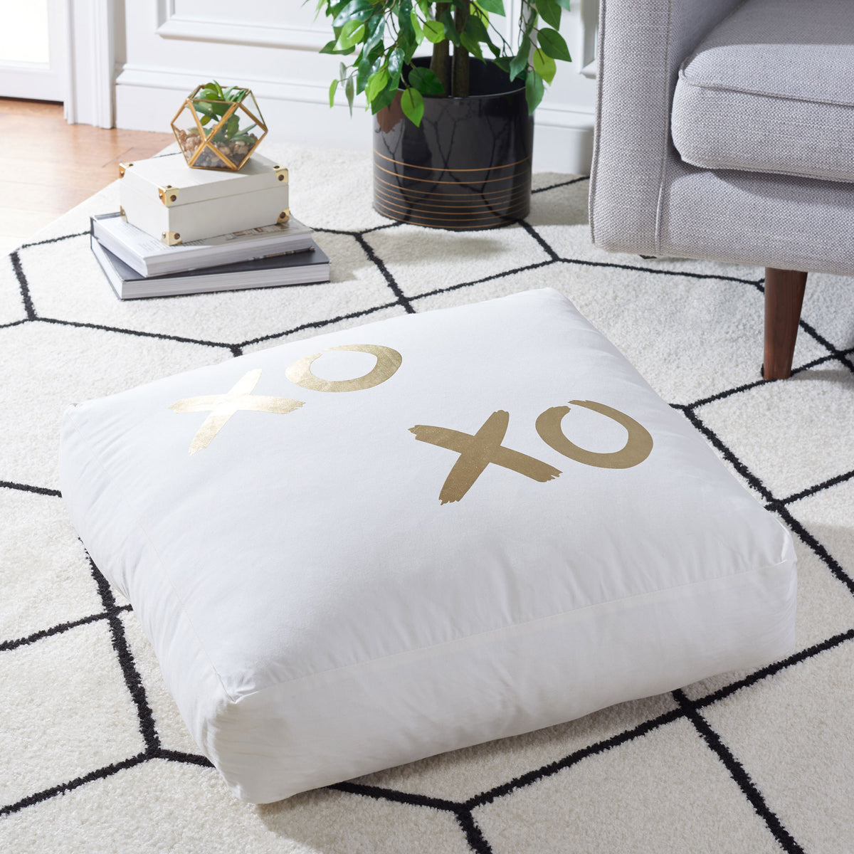 A plush floor pillow with gold X and O motifs offers inviting comfort atop a patterned rug.