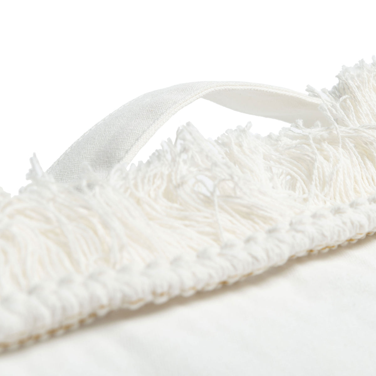 An ivory fabric carry loop rises above feathery fringe along the pillow's edge. || FLP1018A || handle_studio