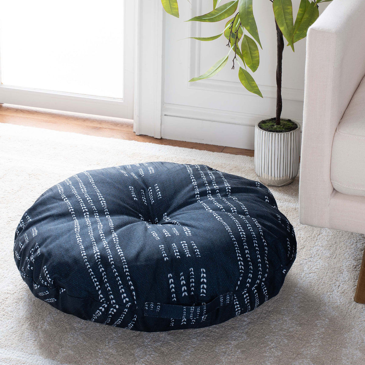 A tufted navy floor pillow with ivory dash stripes adds a cozy place to lounge beside a sofa. || FLP1023A-2626 || front_angle_room