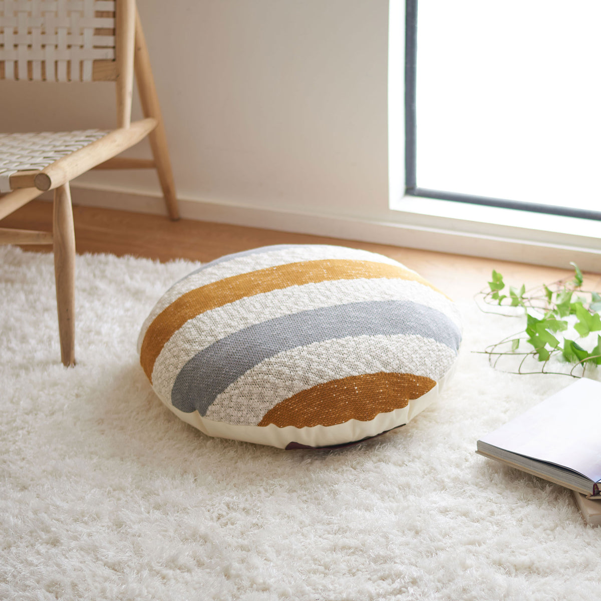 Plush striped floor pillow adds a cozy seat and warm mustard tones to a living space