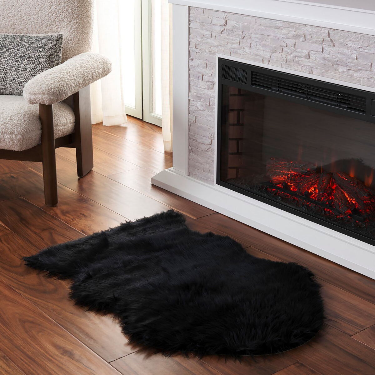 Black faux sheepskin rug with plush shag placed on wood flooring beside a fireplace