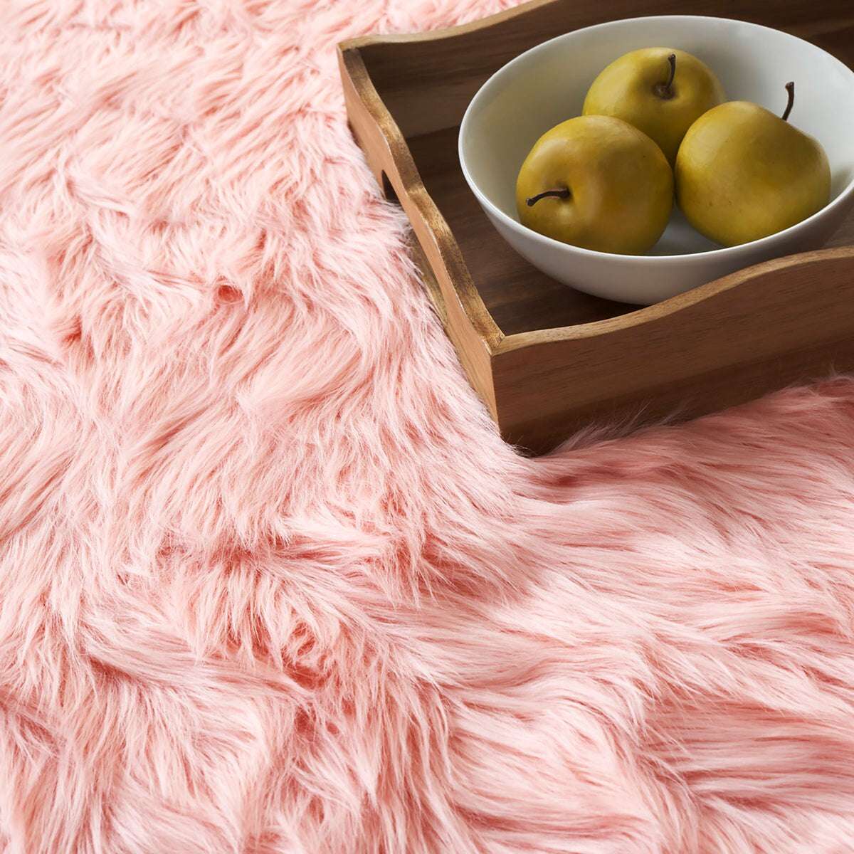Close-up of soft pink faux sheepskin fur beside a wooden tray holding a bowl of pears || FSS235G-2 || detail_room
