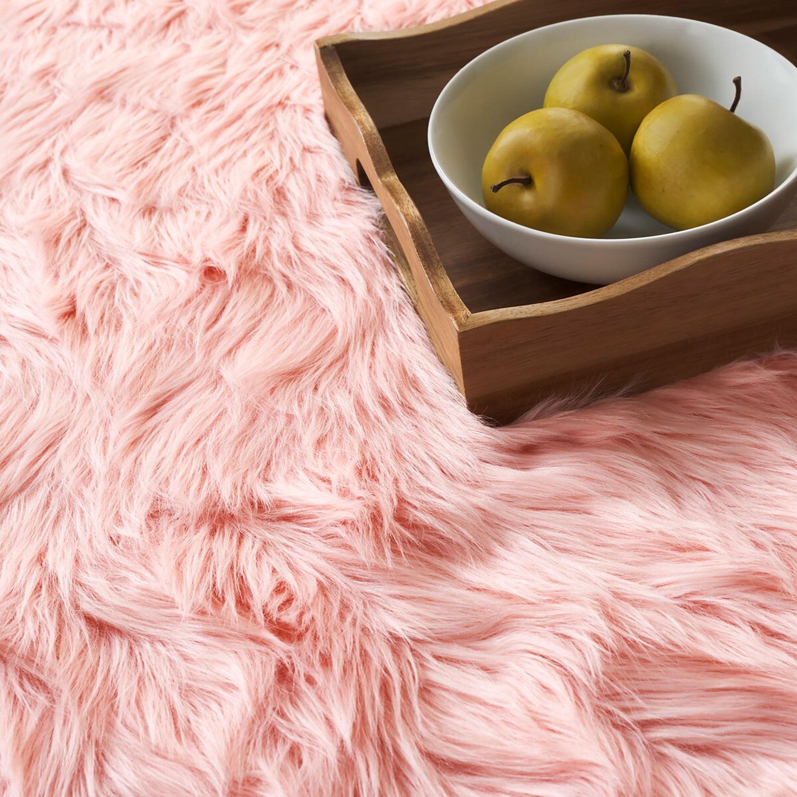 Close-up of soft pink faux sheepskin fur beside a wooden tray holding a bowl of pears || FSS235G-2 || detail_room