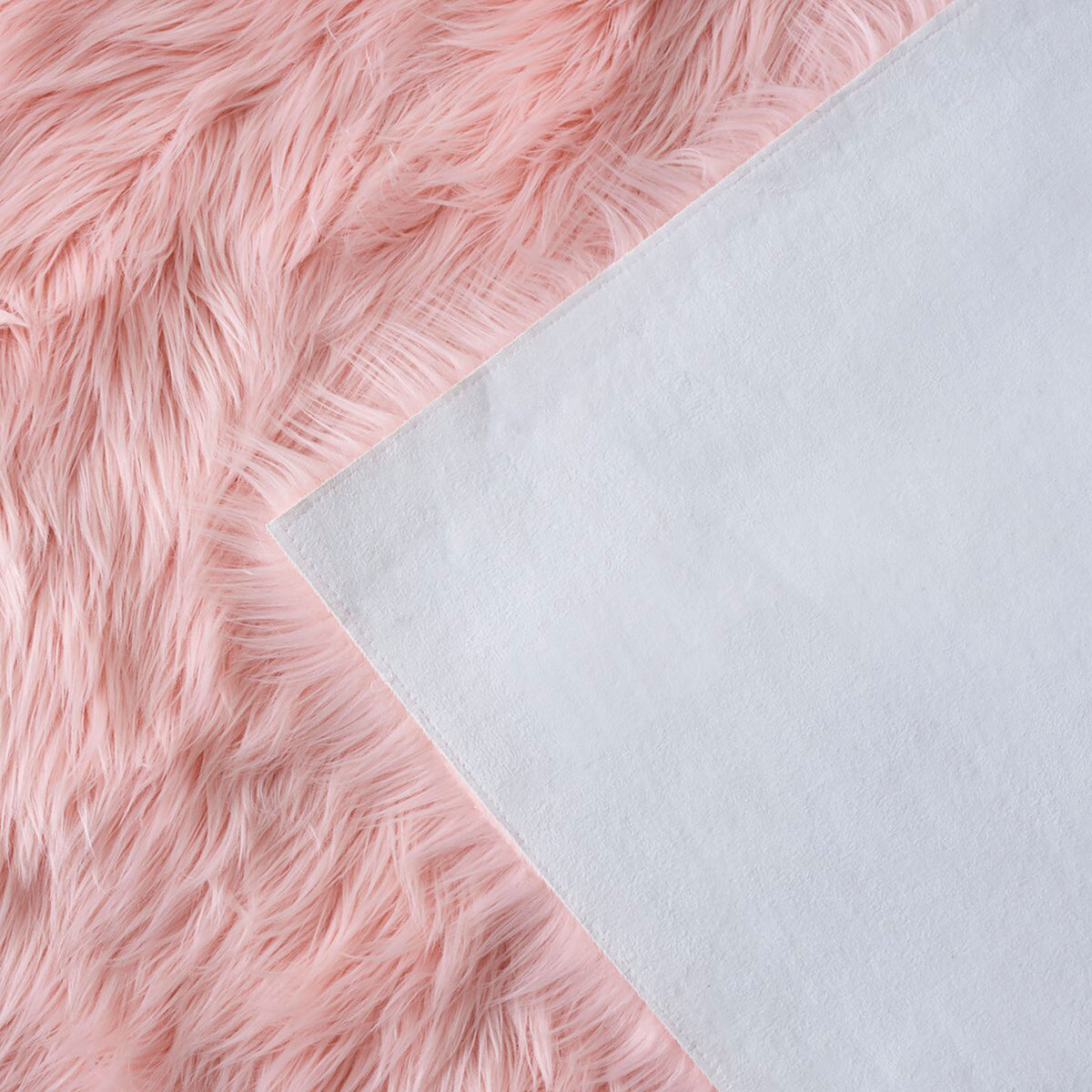 Folded pink faux sheepskin rug revealing its soft white fabric backing and long shag fibers || FSS235G-5 || backing_studio