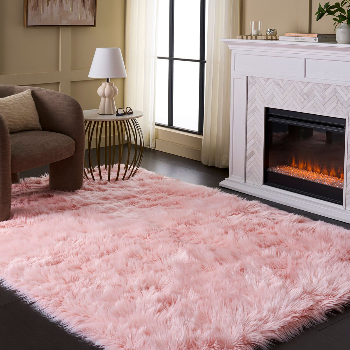 Plush pink faux sheepskin area rug on dark wood flooring in a living room with a fireplace || FSS235G-5 || top_angle_room