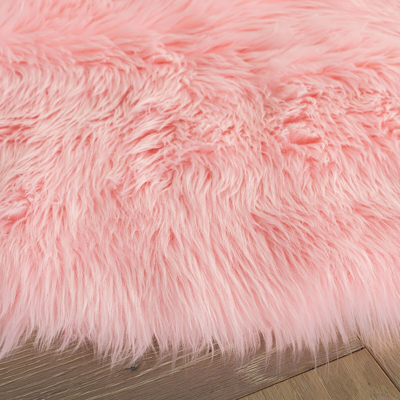Close-up of pink faux sheepskin rug fibers and fluffy edges resting on light wood flooring || FSS235G-5R || detail_room