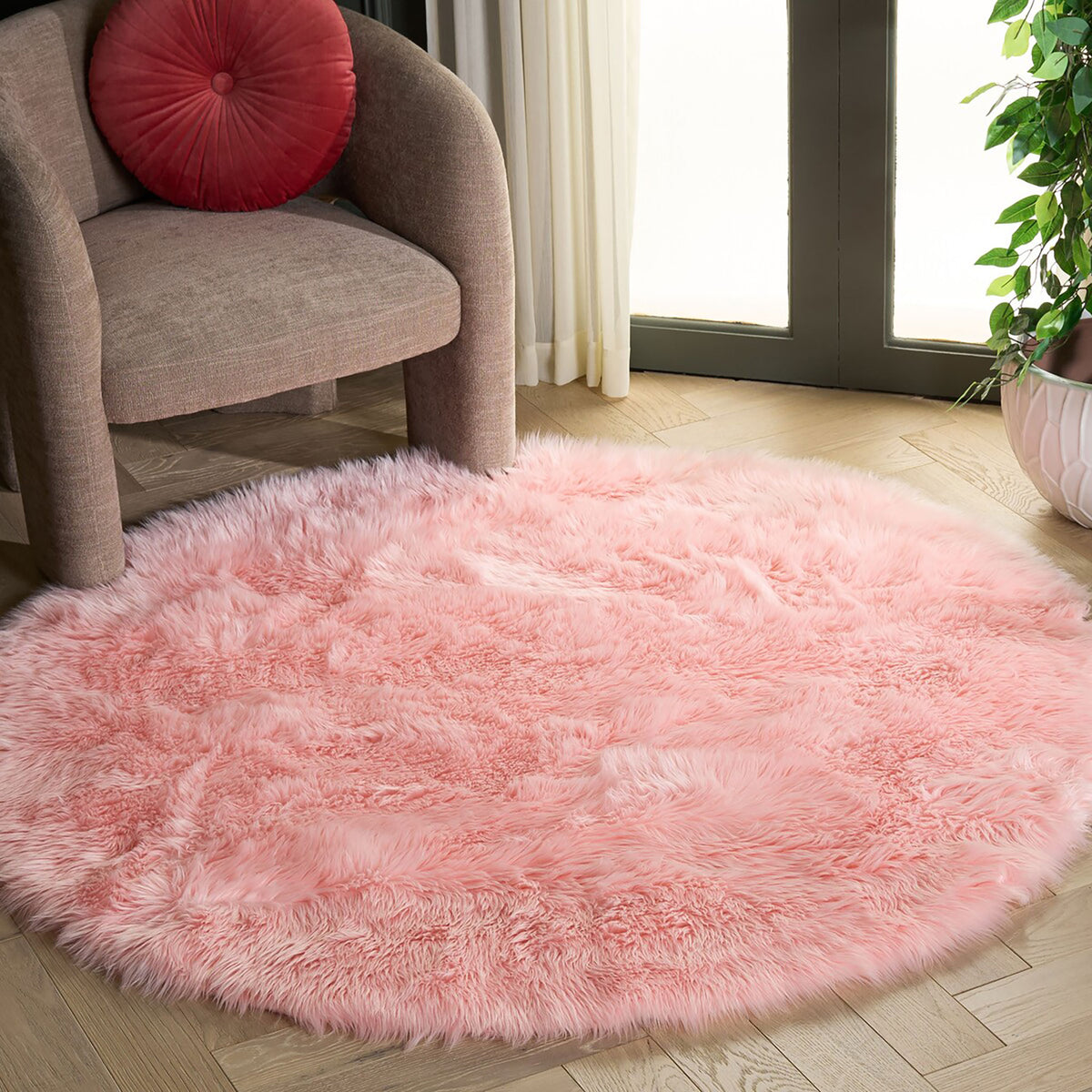 Round pink faux sheepskin rug with plush shag in a living room beside an upholstered chair