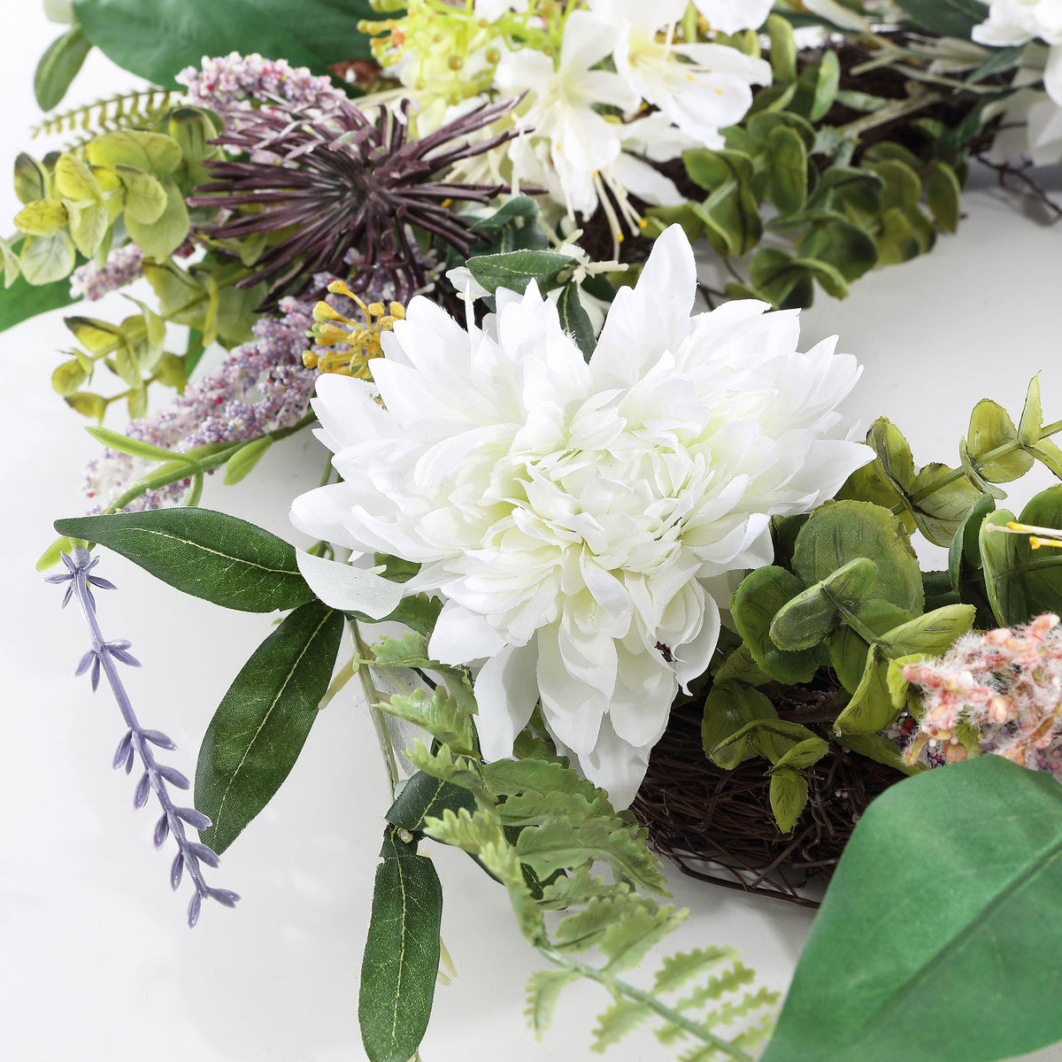 A layered white dahlia sits among olive leaves and delicate stems.