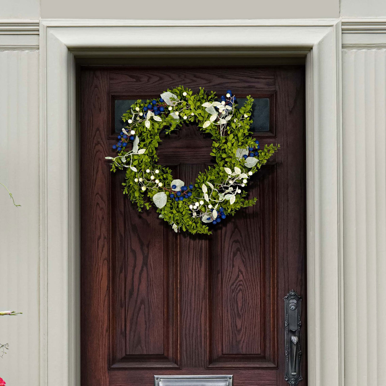 Blue and white berries brighten a green boxwood wreath on a wood door. || FXP1038A || front_room