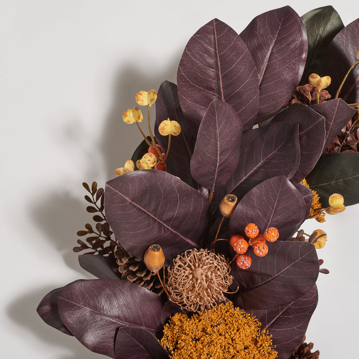 Deep plum leaves mingle with orange berries and textured seed pods.