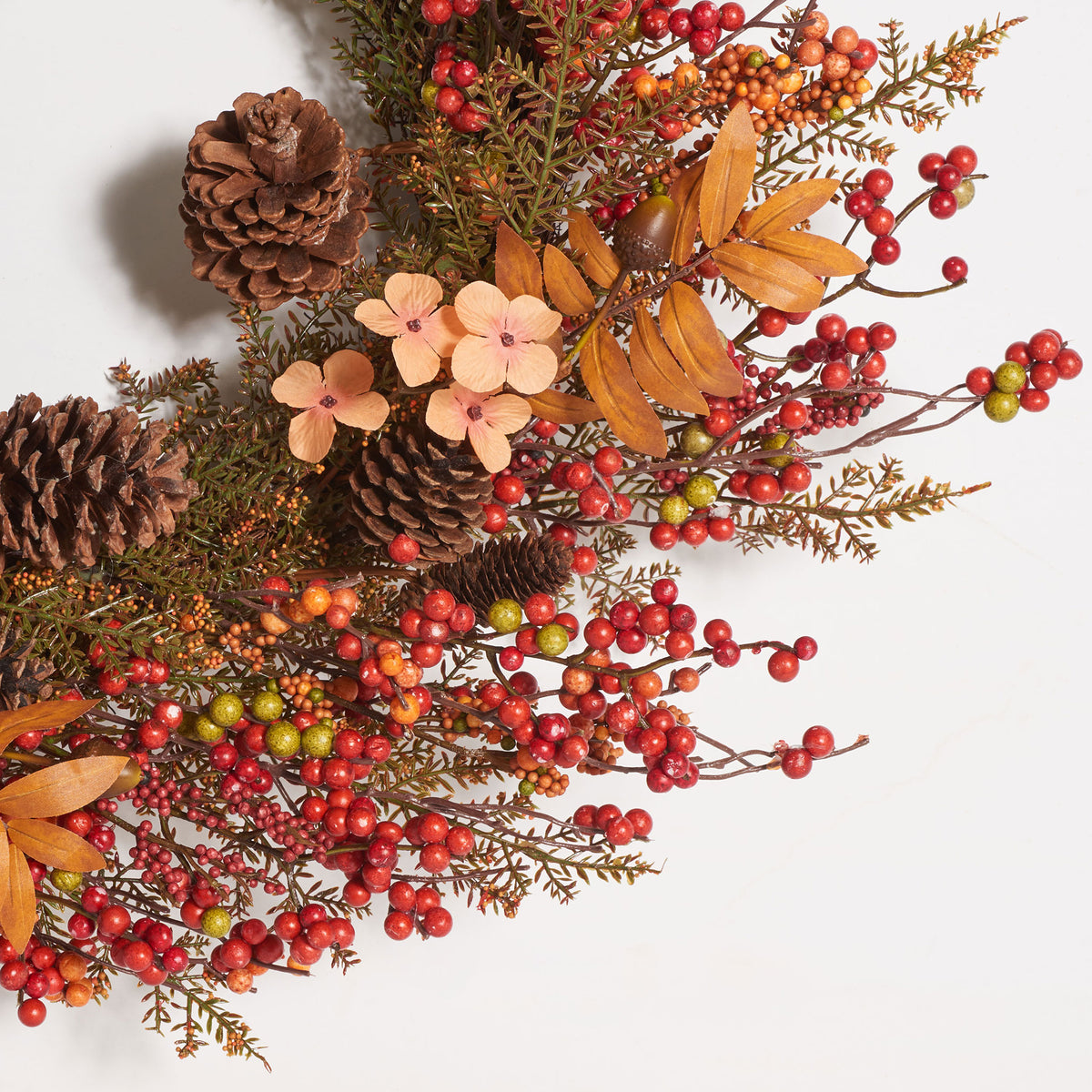 Red and orange berries surround pale blossoms, pine cones, and coppery leaves. || FXP1050A || detail_studio