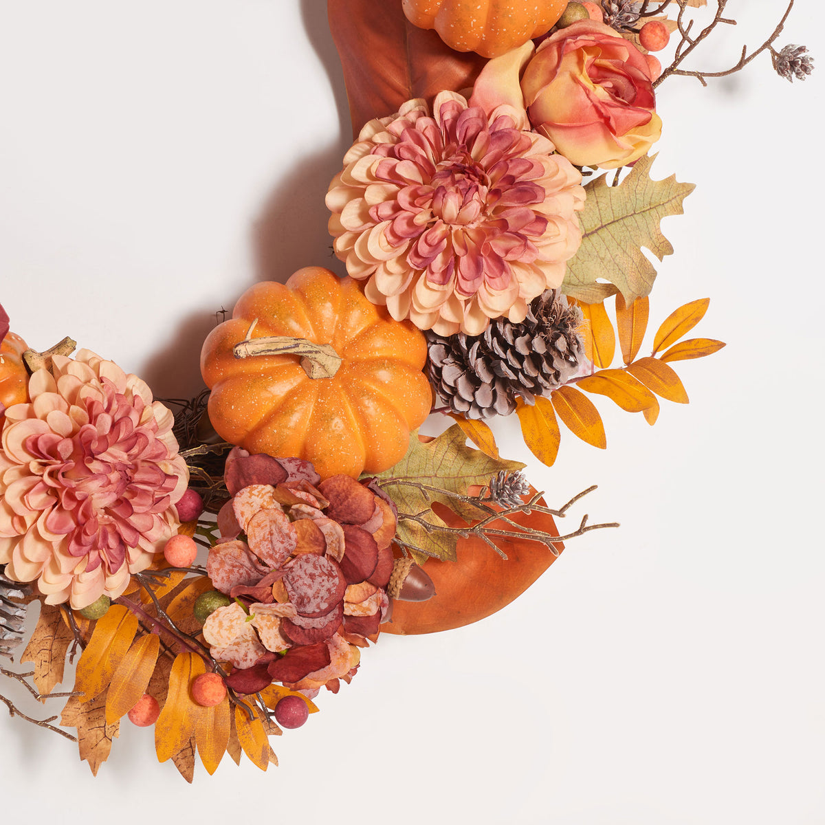A bright pumpkin nestles among layered pink blooms and pine cones. || FXP1053A || detail_studio