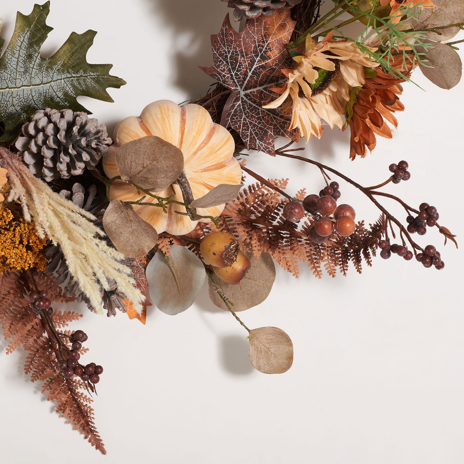 A striped pumpkin rests among berries, frosted pine cones, and autumn leaves. || FXP1056A || detail_studio