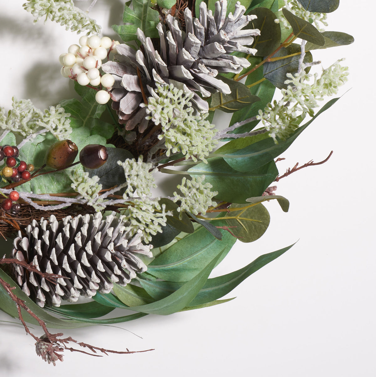 Frosted-looking pine cones nestle among berries and layered green leaves. || FXP1072A || detail_studio