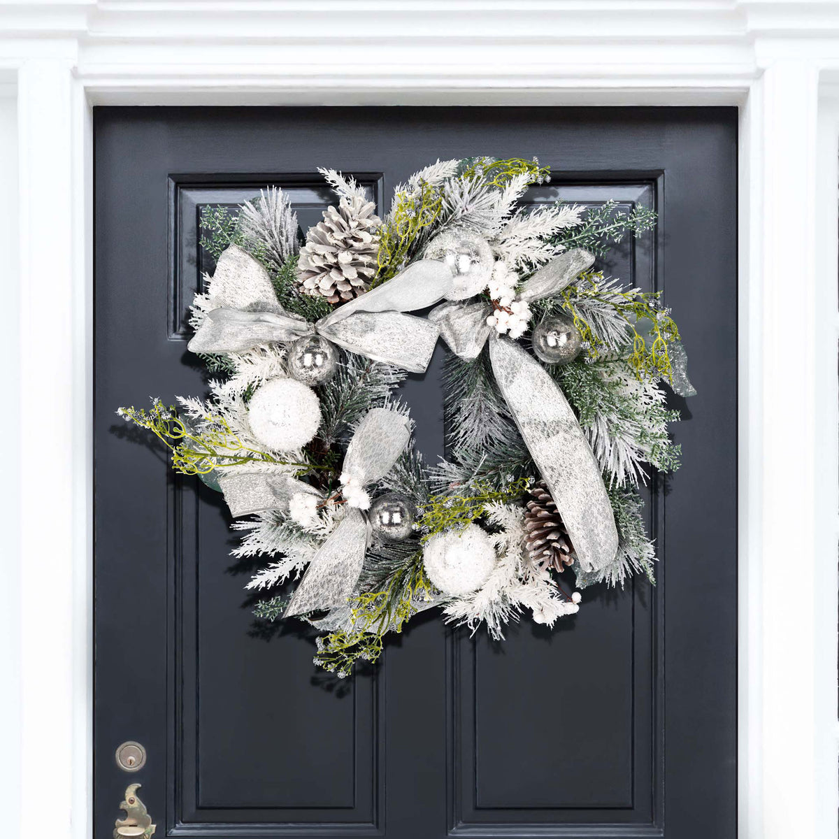 Snowy pine, silver ornaments, and ribbon brighten a dark entry door. || FXP1077A || front_room