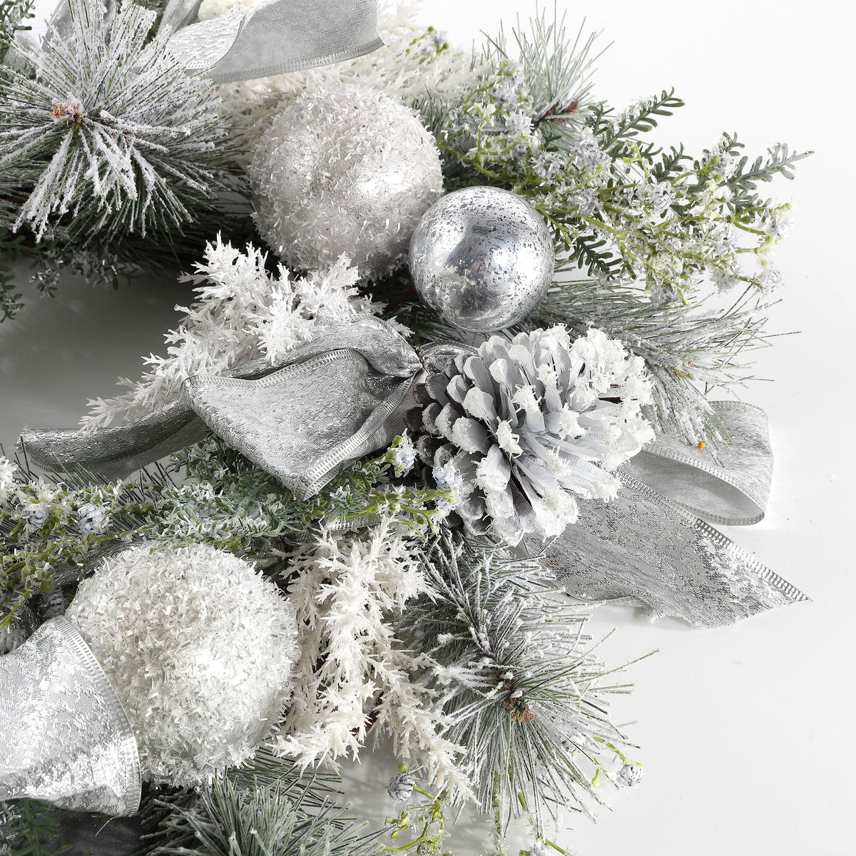 A pale pine cone nestles among glittering silver ornaments and snowy sprigs. || FXP1077A || detail_studio
