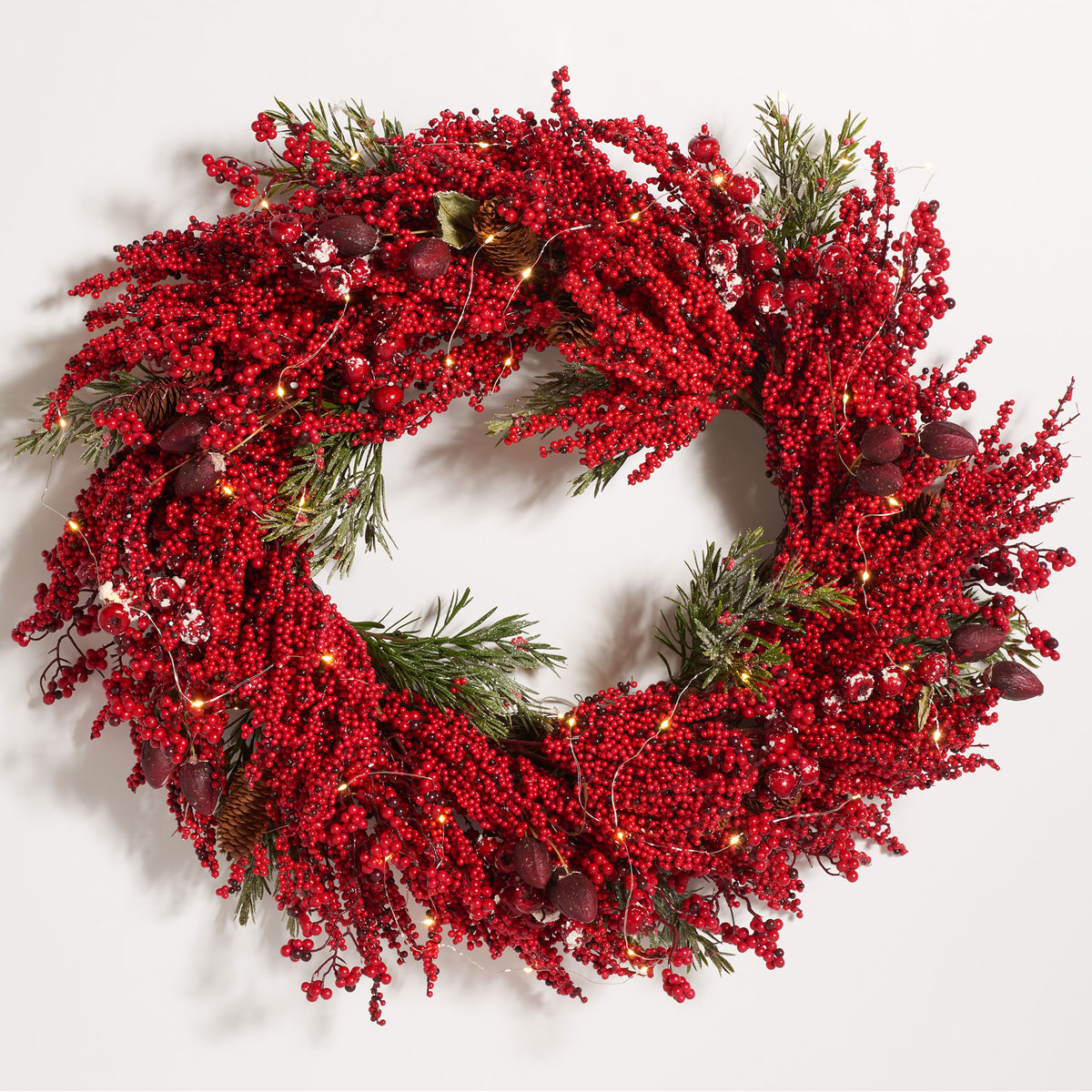 Warm LED lights twinkle among vivid red berries and pine branches. || FXP1093A || front_on_studio