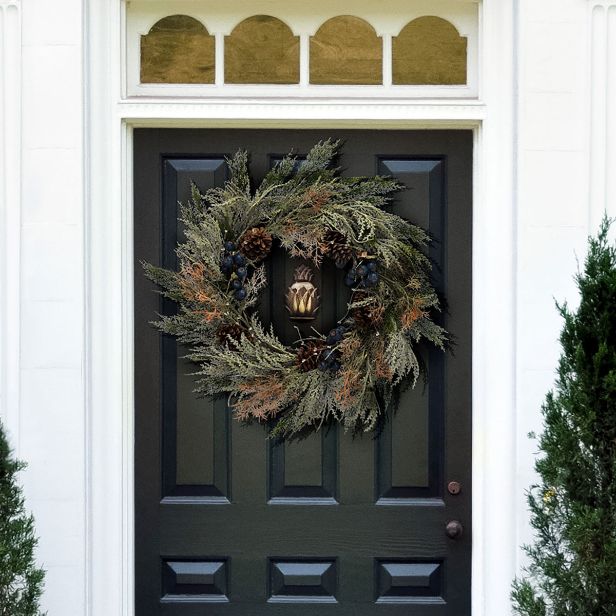 Frosted pine branches and blue berries add wintry charm to a dark door. || FXP1094A || front_room