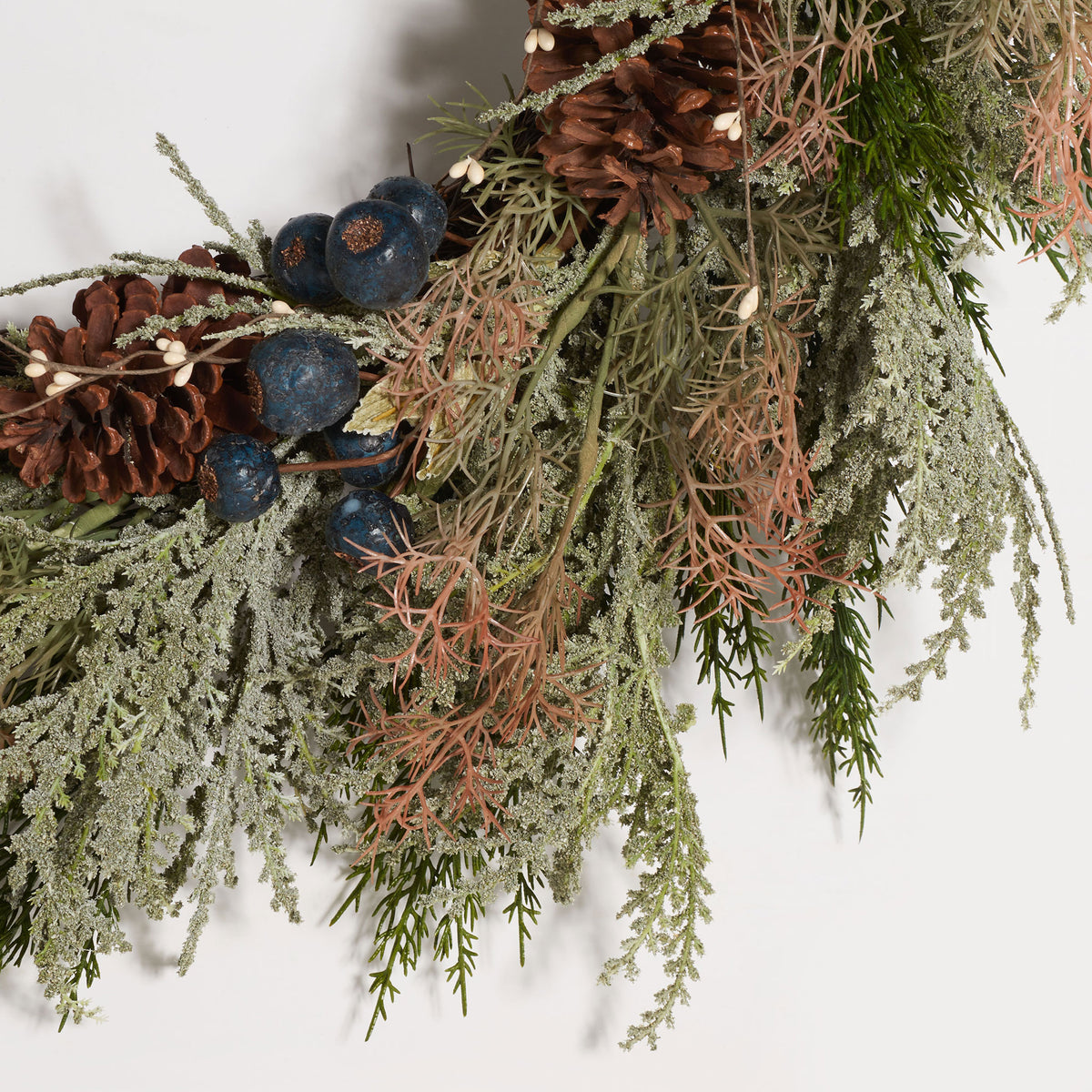 Blue berries and brown pine cones stand out amid pale evergreen sprigs. || FXP1094A || detail_studio