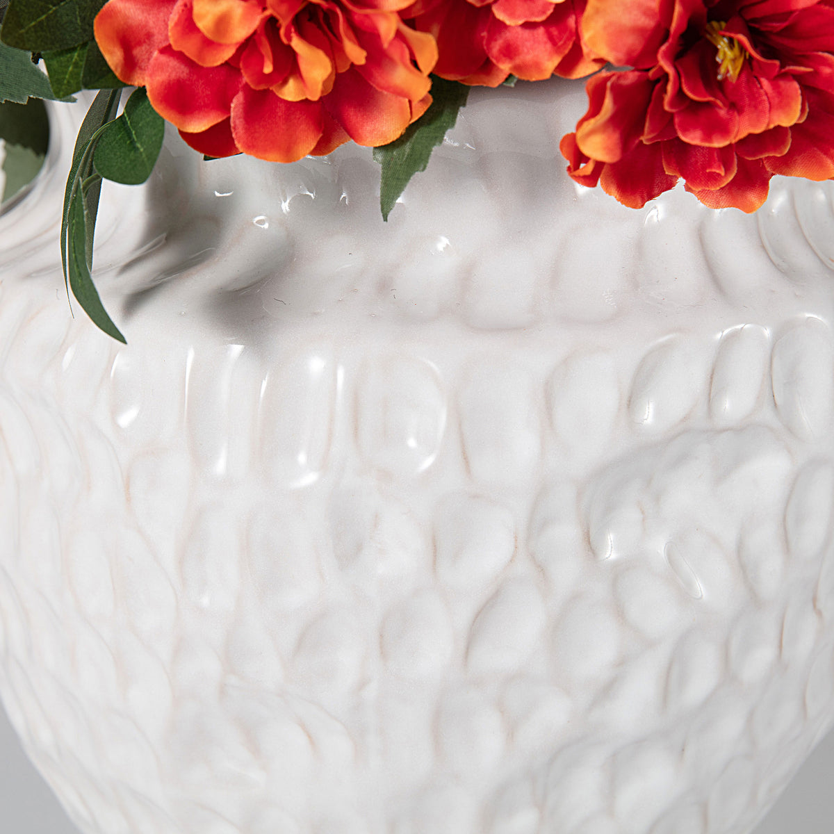 A glossy white planter has raised, organic texture beneath the flowers. || FXP2030A || leg_studio