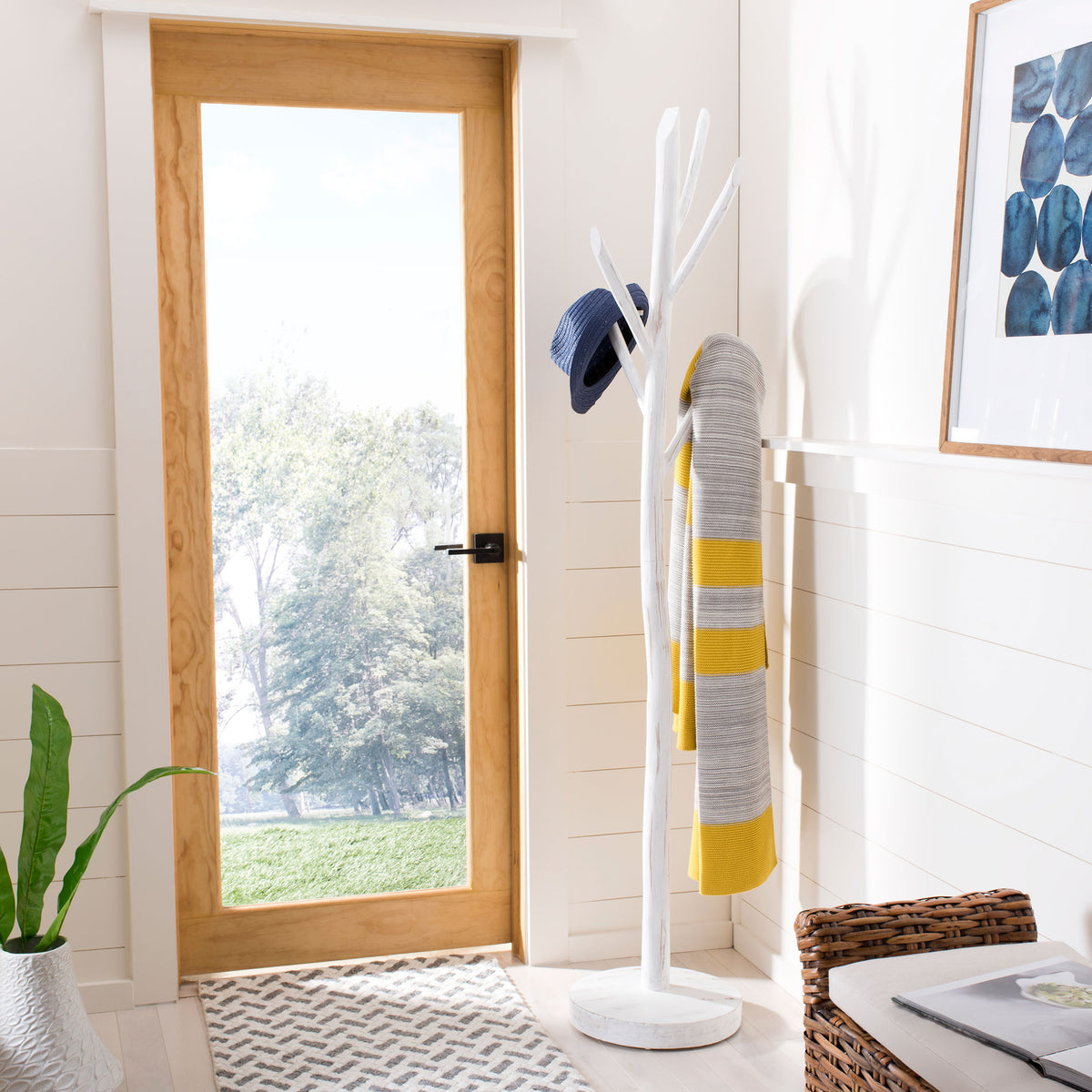 White branch-style coat rack holds a hat and striped scarf near the doorway