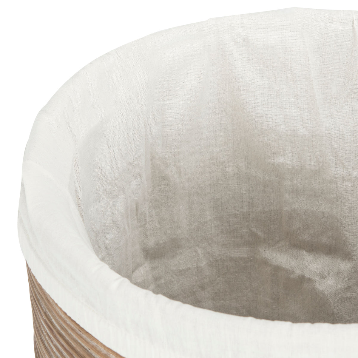 Soft white fabric lines the hamper interior and folds neatly over its rattan rim