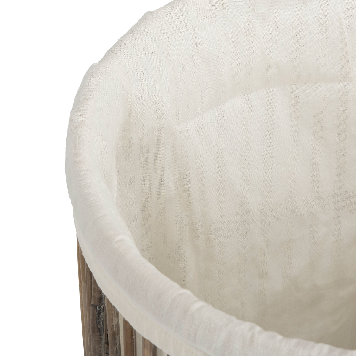 A soft white fabric liner neatly lines the interior of the woven rattan hamper