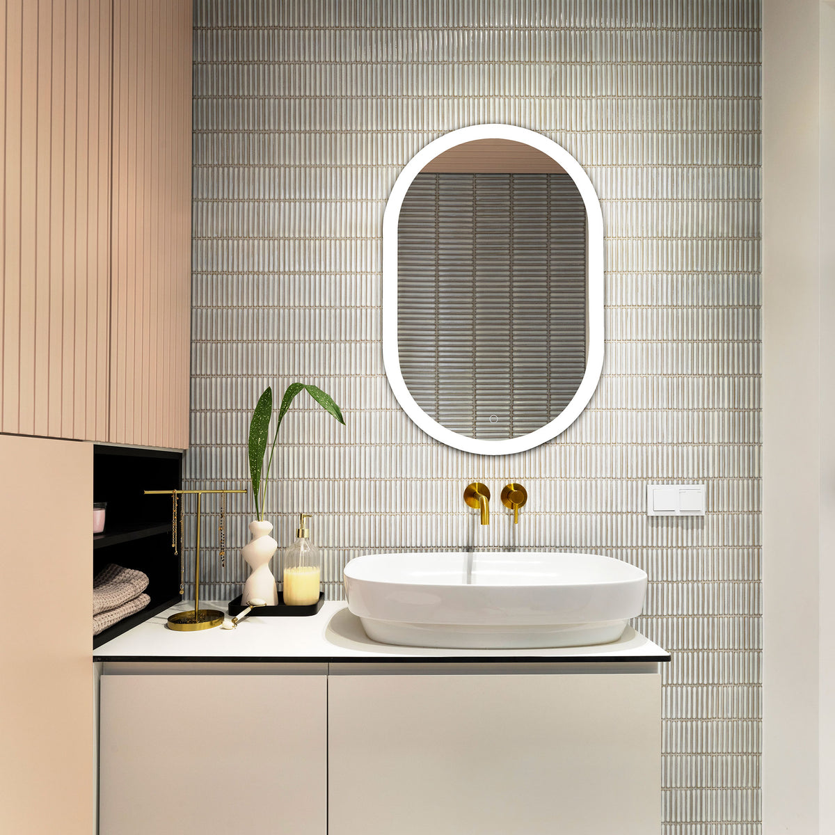 Illuminated oval LED mirror casts a bright glow above a tiled bathroom vanity || LMR1009A || front_on_room