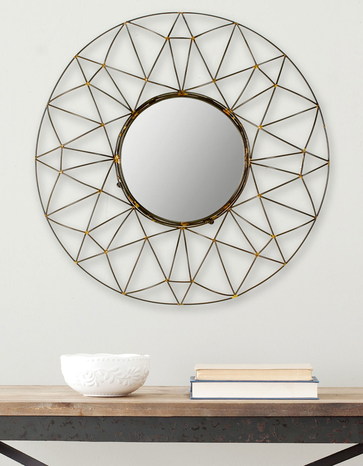 Geometric bronze wirework radiates around a circular mirror above a wood console. || MIR4015A || front_room