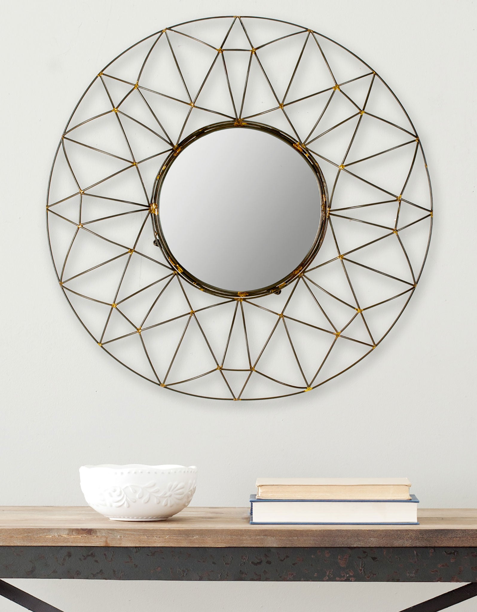 Geometric bronze wirework radiates around a circular mirror above a wood console. || MIR4015A || front_room