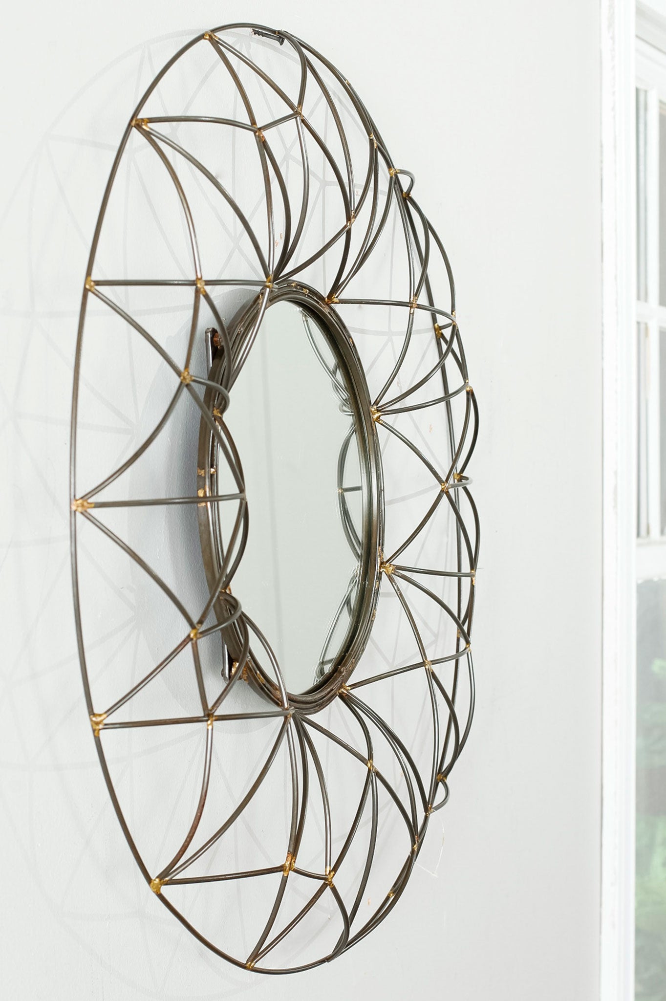 A dimensional bronze wire lattice creates an airy, sculptural frame around the round wall mirror. || MIR4015A || side_room